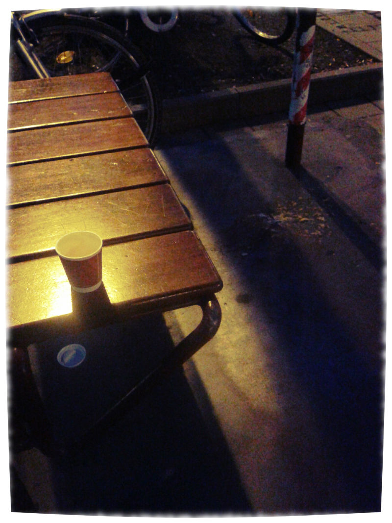 Bushaltestelle im dunklen. Auf der Sitzbank ein Pappbecher fr Kaffee, auf dem Pflaster Kotze.