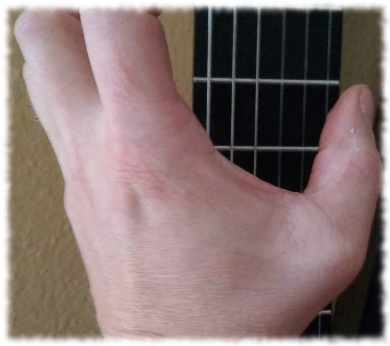 Linke Hand beziehungsweise Daumen vor Gitarrengriffbrett.