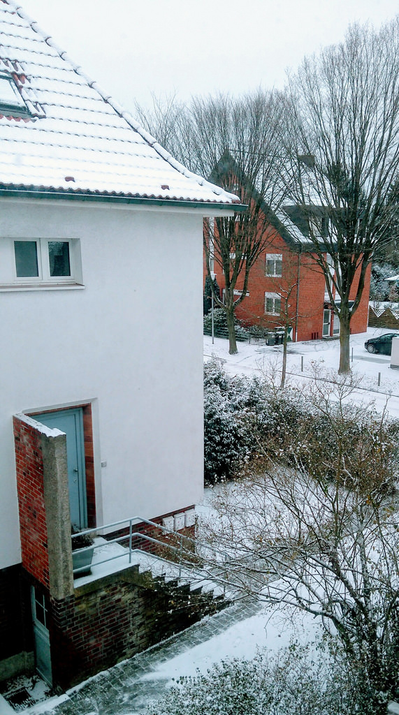 Wohngebiet mit dünner Schneedecke, aufgenommen aus dem Fenster. 